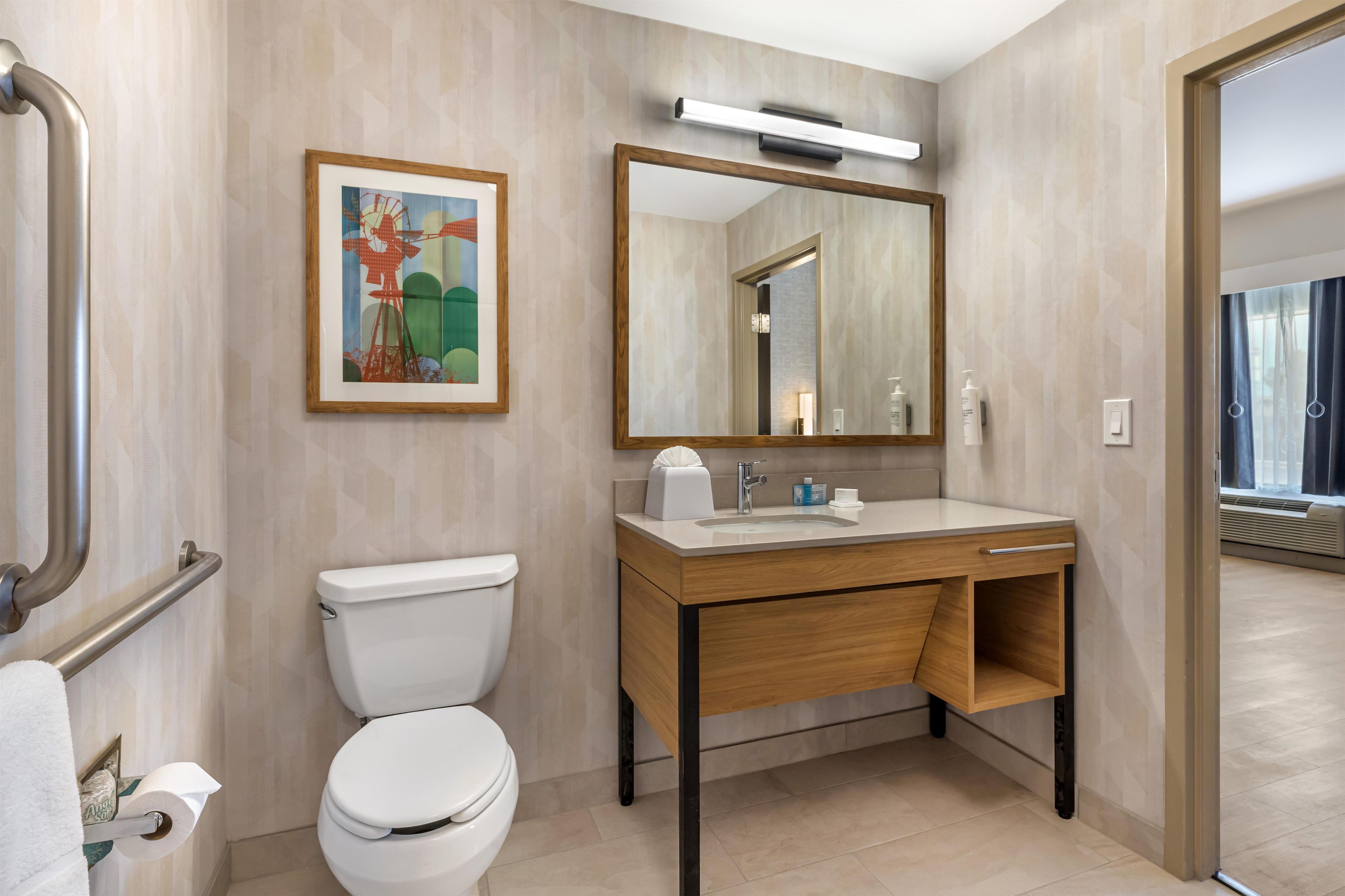 Een moderne badkamer met toilet, wastafel en spiegel.