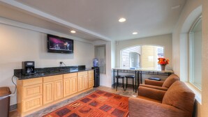 Ett modernt kök med en inbyggd köksö, en matplats med barstolar och en mysig sittgrupp med en soffa.
