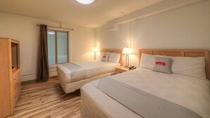 Ett hotellrum med två sängar, en garderob i trä, ett skrivbord och ett fönster med gardiner.