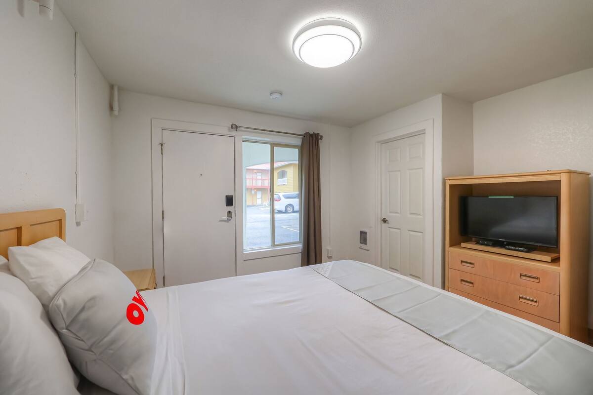 Une chambre d’hôtel avec un lit, une télévision, une porte et une fenêtre.