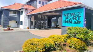 En ny hotellbyggnad, New Port Inn, med ett rött tegeltak, en överbyggd entré och en skylt.