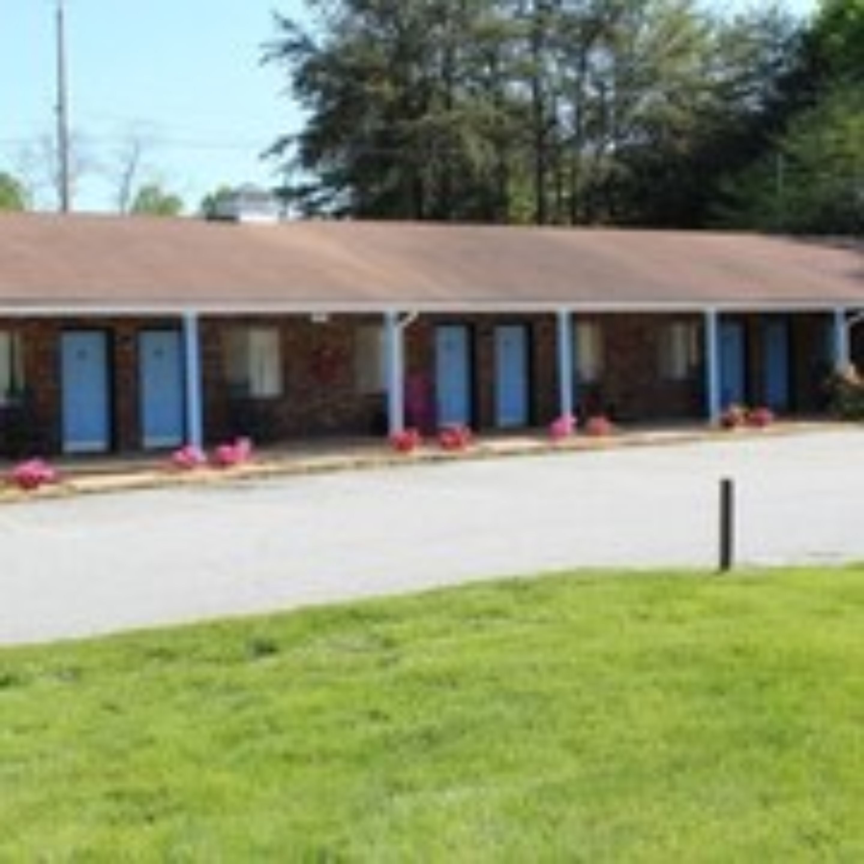 Un motel con una fila de habitaciones, cada una con puerta y un pequeño porche.
