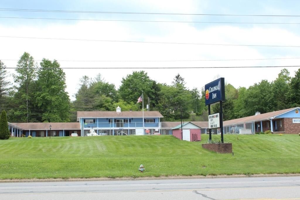 Een Colonial Inn motel met een grote bord, een gazon en een gebouw met een blauw dak.