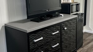 Un mueble multimedia negro con un televisor de pantalla plana, un microondas y un reproductor de DVD.