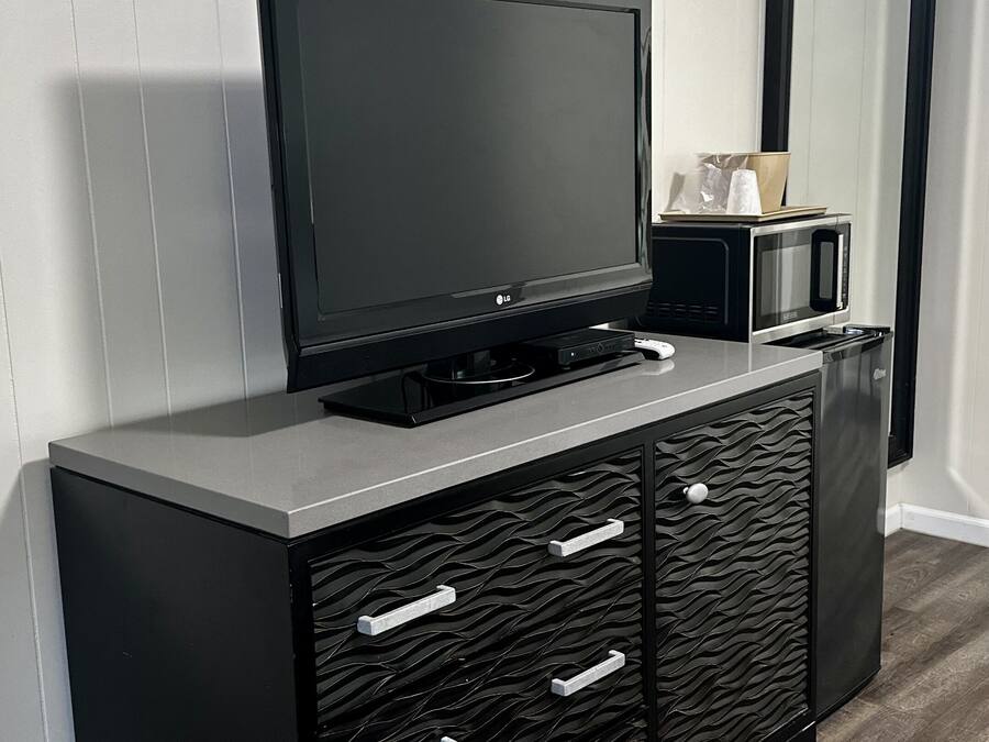 A black entertainment unit with a flat-screen TV, a microwave, and a DVD player.
