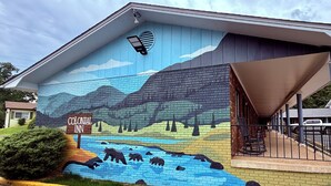 Un edificio con un mural que muestra un paisaje con montañas, árboles y osos junto a un río.