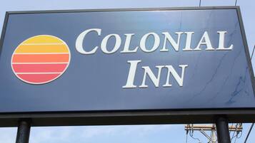 Une enseigne pour le Colonial Inn, avec un logo comportant des rayures horizontales de couleur jaune, orange et rouge.