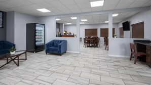 Une pièce spacieuse comprenant un coin repas, un réfrigérateur et un canapé bleu.