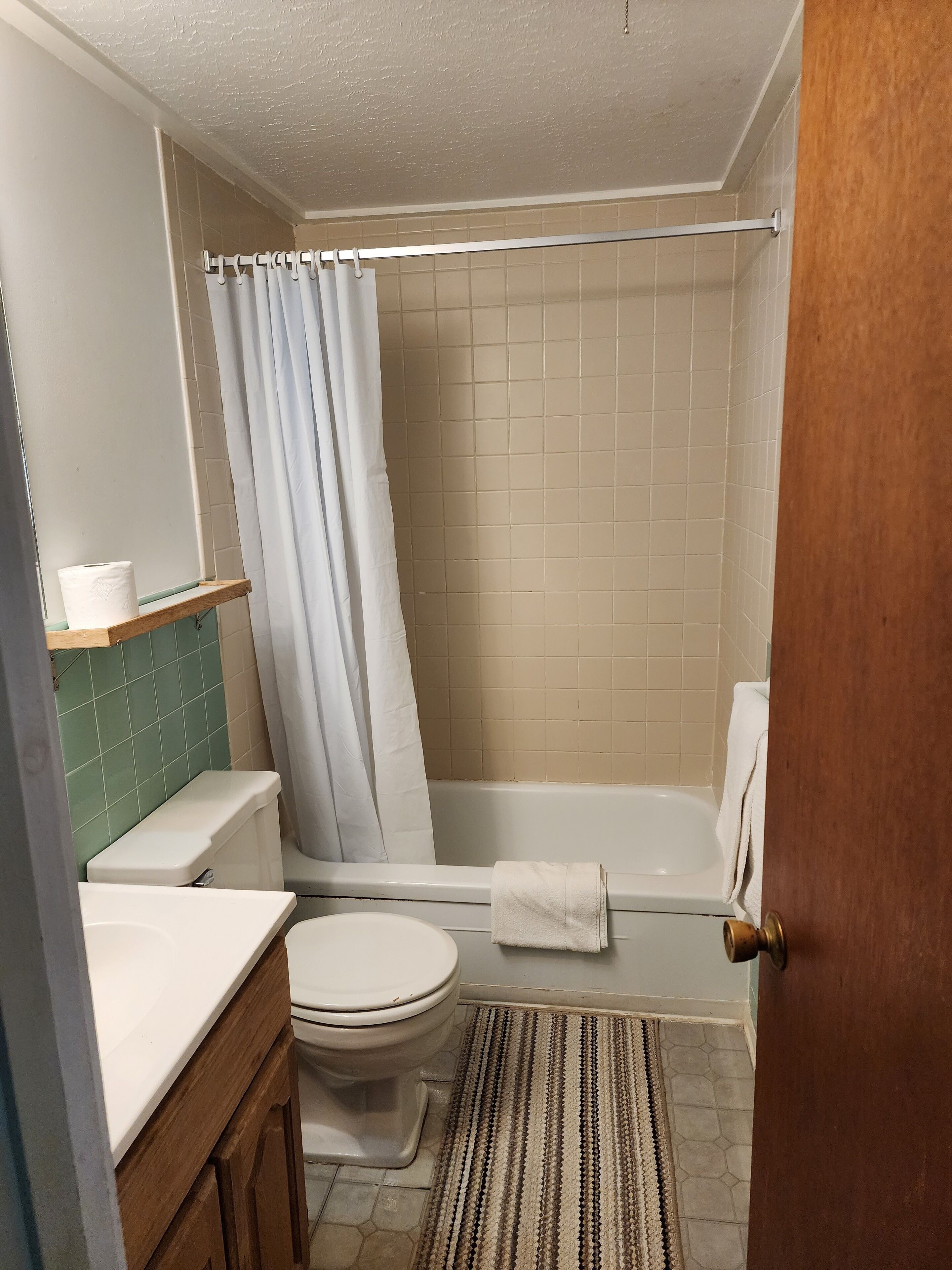 Un baño con inodoro, lavabo, bañera y cortina de ducha.