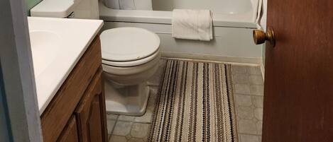 Ein Badezimmer mit Toilette, Waschbecken, Badewanne und Duschvorhang.