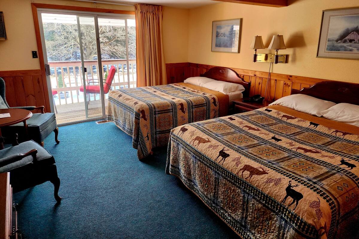 A hotel room with two beds, a desk, and a chair.
