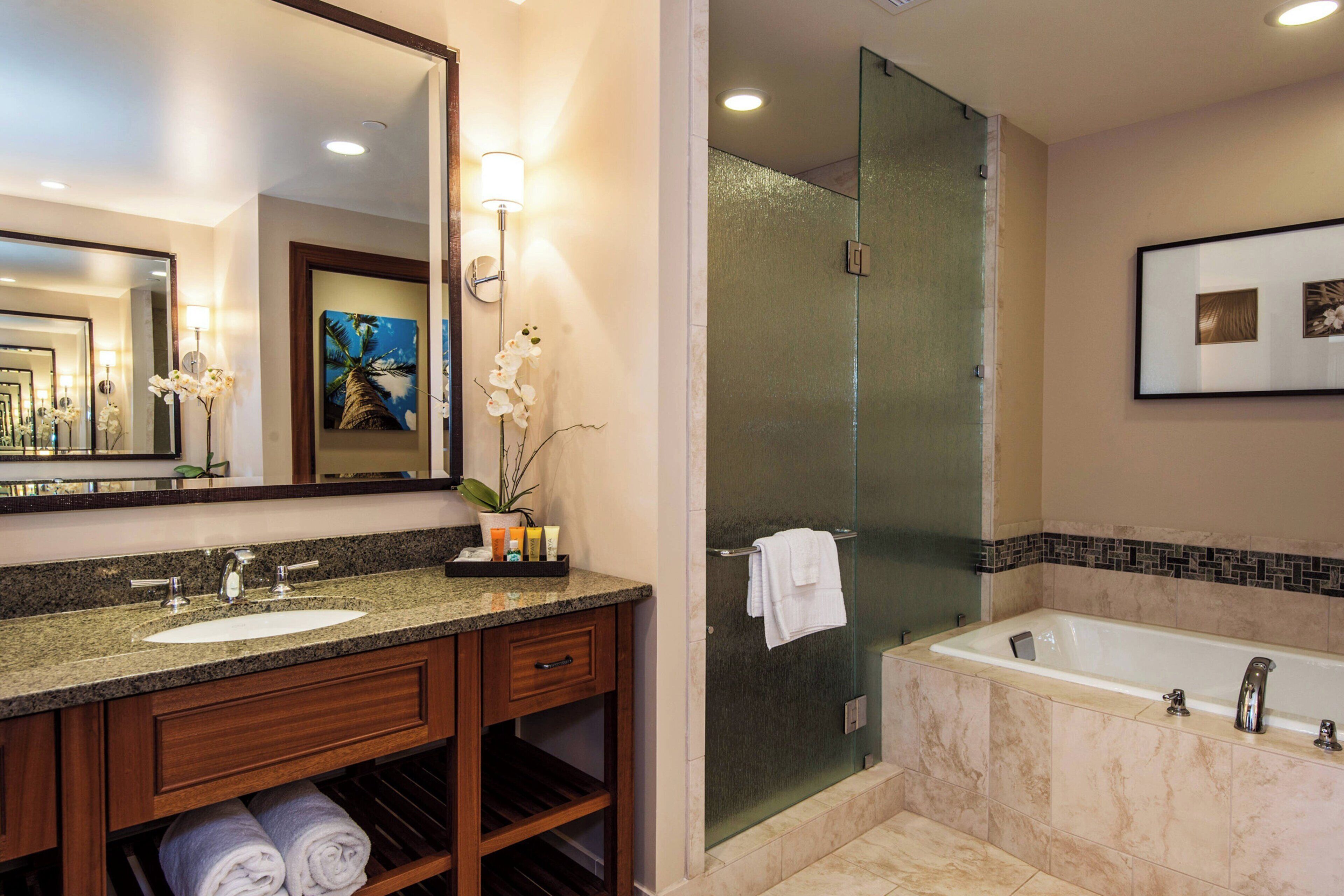 A bathroom with a double sink vanity, a glass-enclosed shower, and a bathtub.