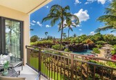 A balcony with a view of a tropical garden, a pool, and a waterfall.