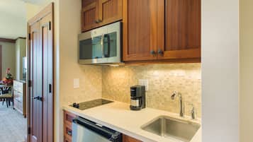 A kitchen with wooden cabinets, a stainless steel dishwasher, a coffee maker, and a tiled backsplash.