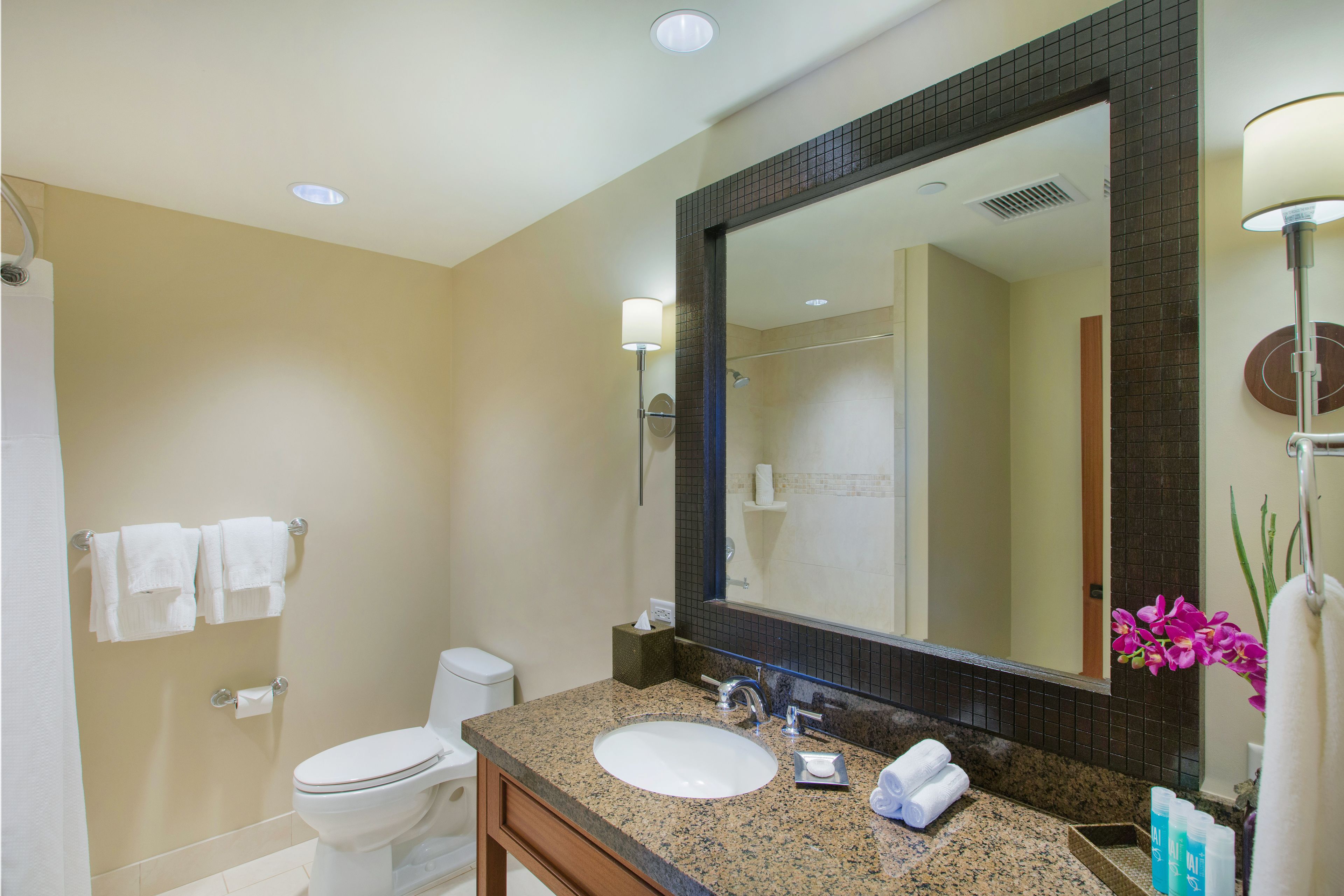 A bathroom with a sink, mirror, toilet, and towels.