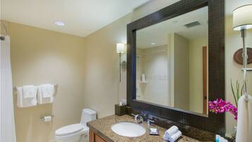 A bathroom with a sink, mirror, toilet, and towels.