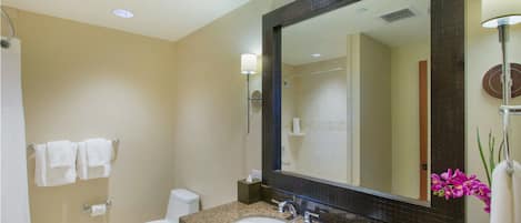 Une salle de bain équipée d’un lavabo, d’un miroir, de toilettes et de serviettes.