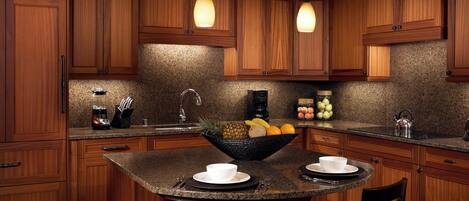A kitchen with wooden cabinets, granite countertops, a central island with seating, and pendant lighting.