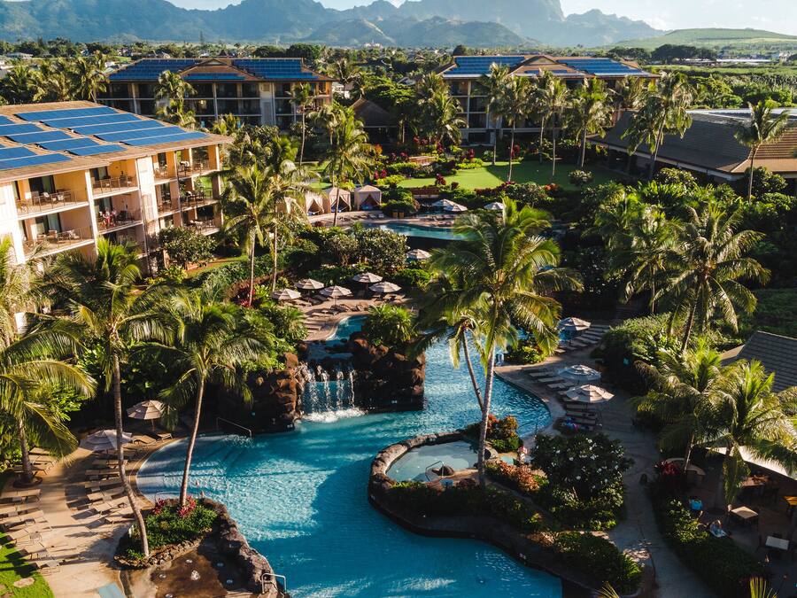 Ein Resort mit mehreren Swimmingpools, Palmen und einer Bergkulisse.