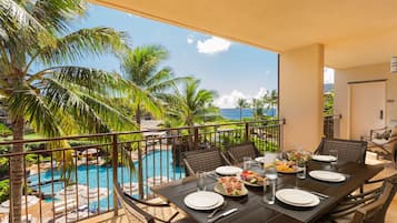 Un comedor con una mesa dispuesta para dos, con vista a una piscina y palmeras.