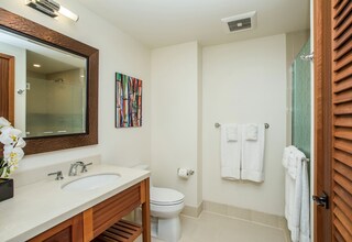 A modern bathroom with a double sink vanity, a toilet, and a shower area.