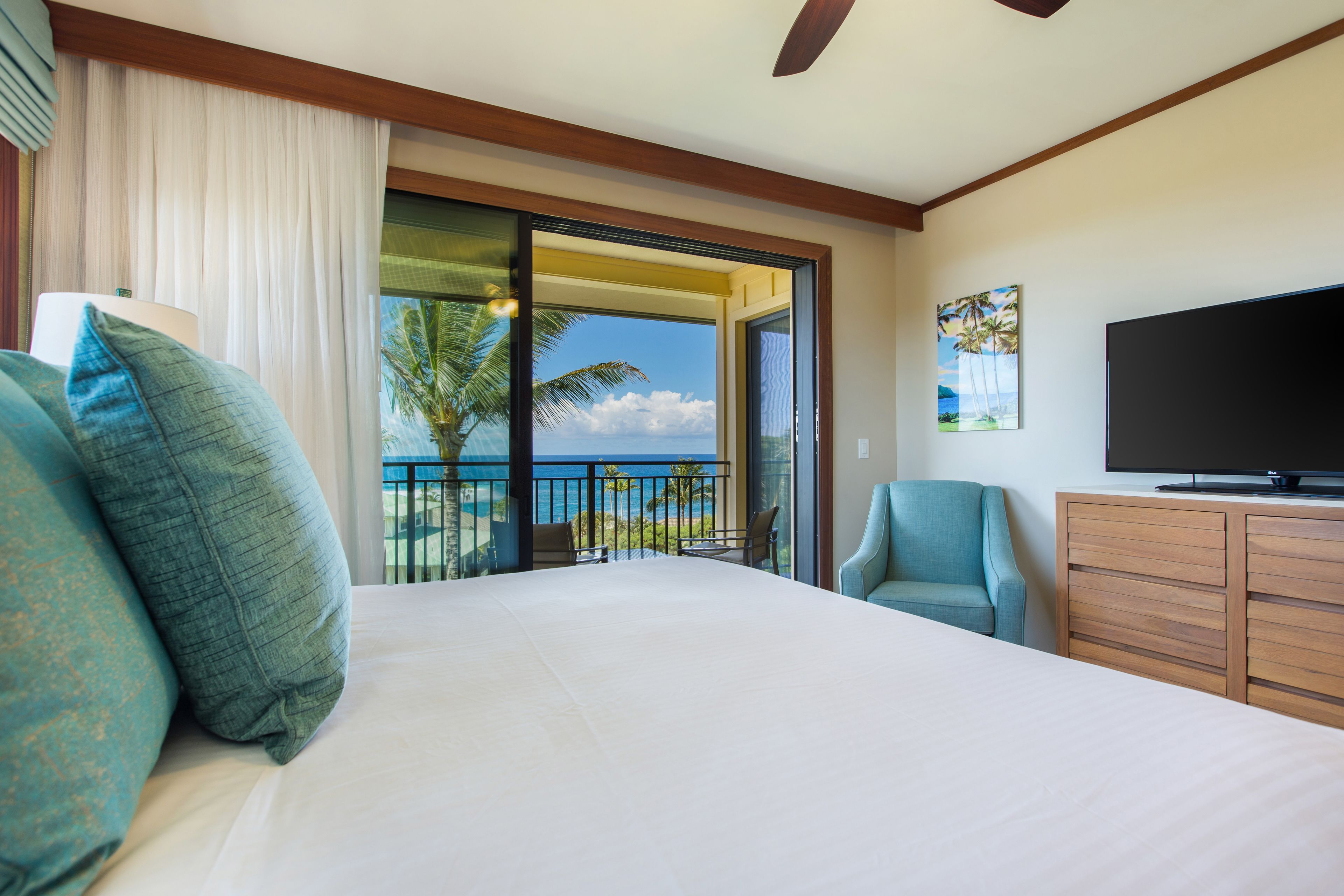 Ein Hotelzimmer mit Bett, Fernseher, Schreibtisch und Meerblick.