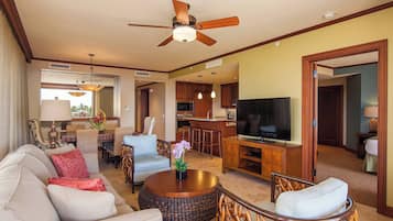A spacious living area with a ceiling fan, a television, and a dining area with wicker furniture.