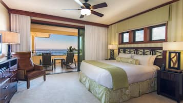 Habitación de hotel con cama, escritorio, silla, ventilador de techo y vista al océano.