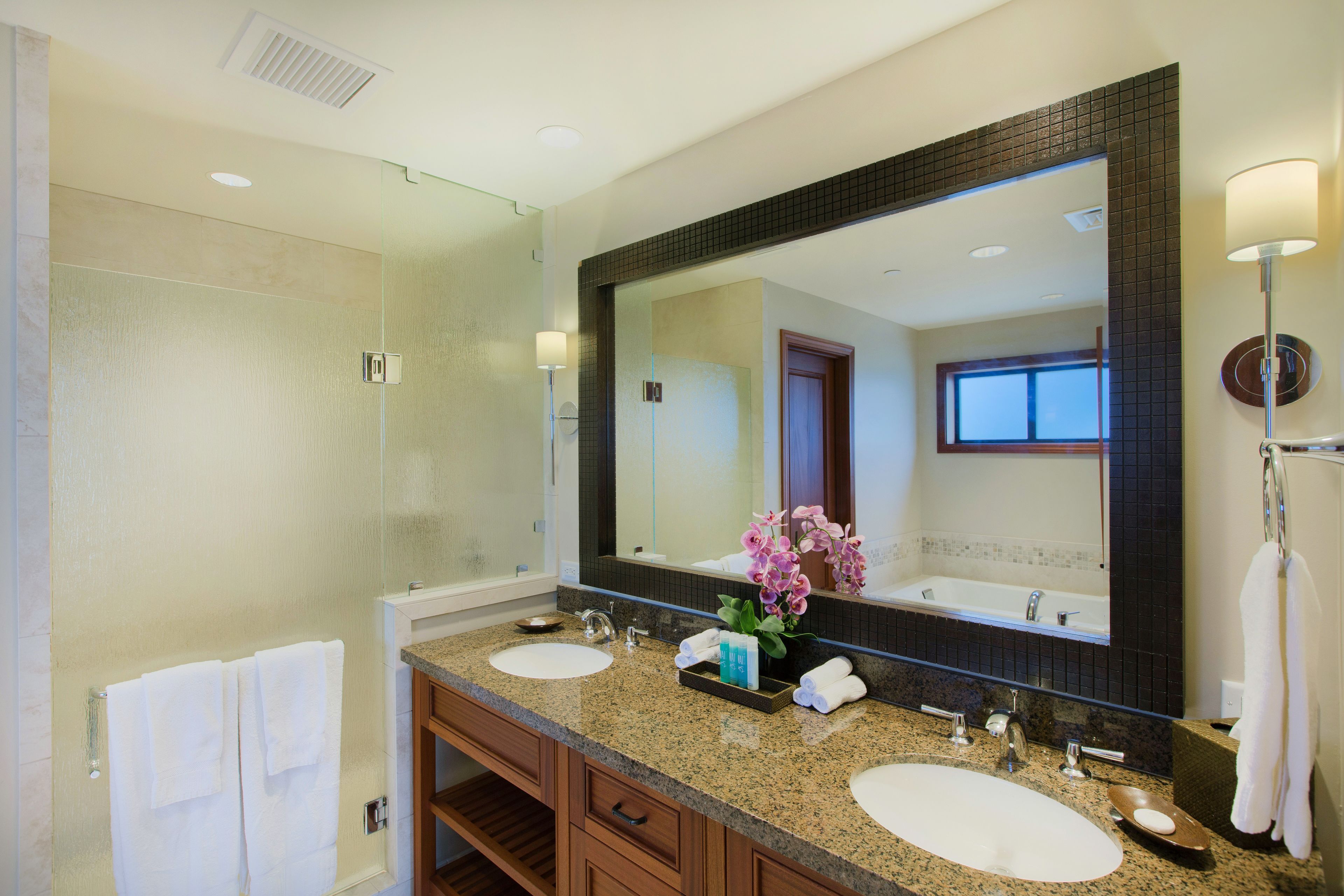 A bathroom with two sinks, a large mirror, and a shower.