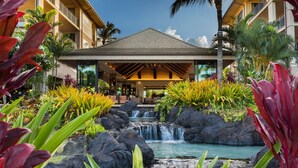 A hotel with a waterfall, lush tropical plants, and a covered entrance. - Koloa Landing Resort at Poipu, Autograph Collection (Koloa)
