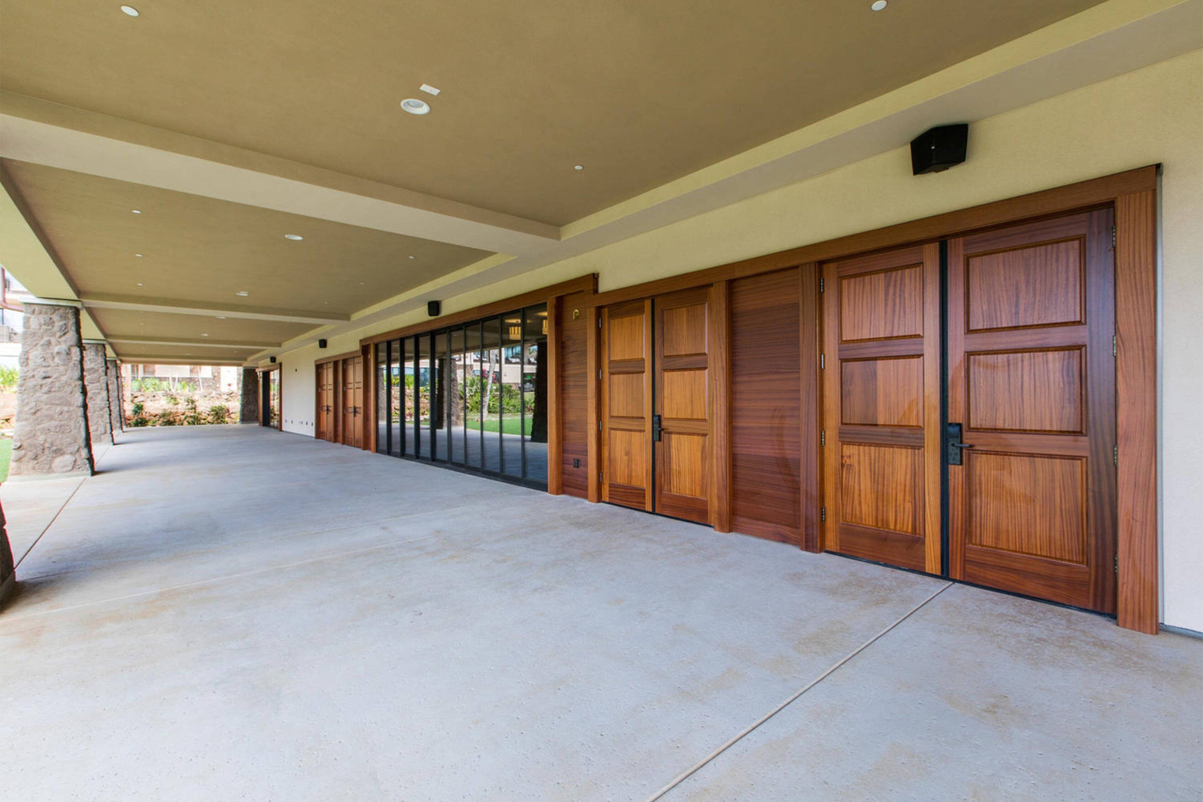 A covered outdoor area with a concrete floor, wooden doors, and a stone pillar.