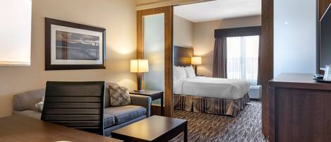 Habitación de hotel con cama, sofá, escritorio con teléfono, lámpara y un cuadro en la pared.