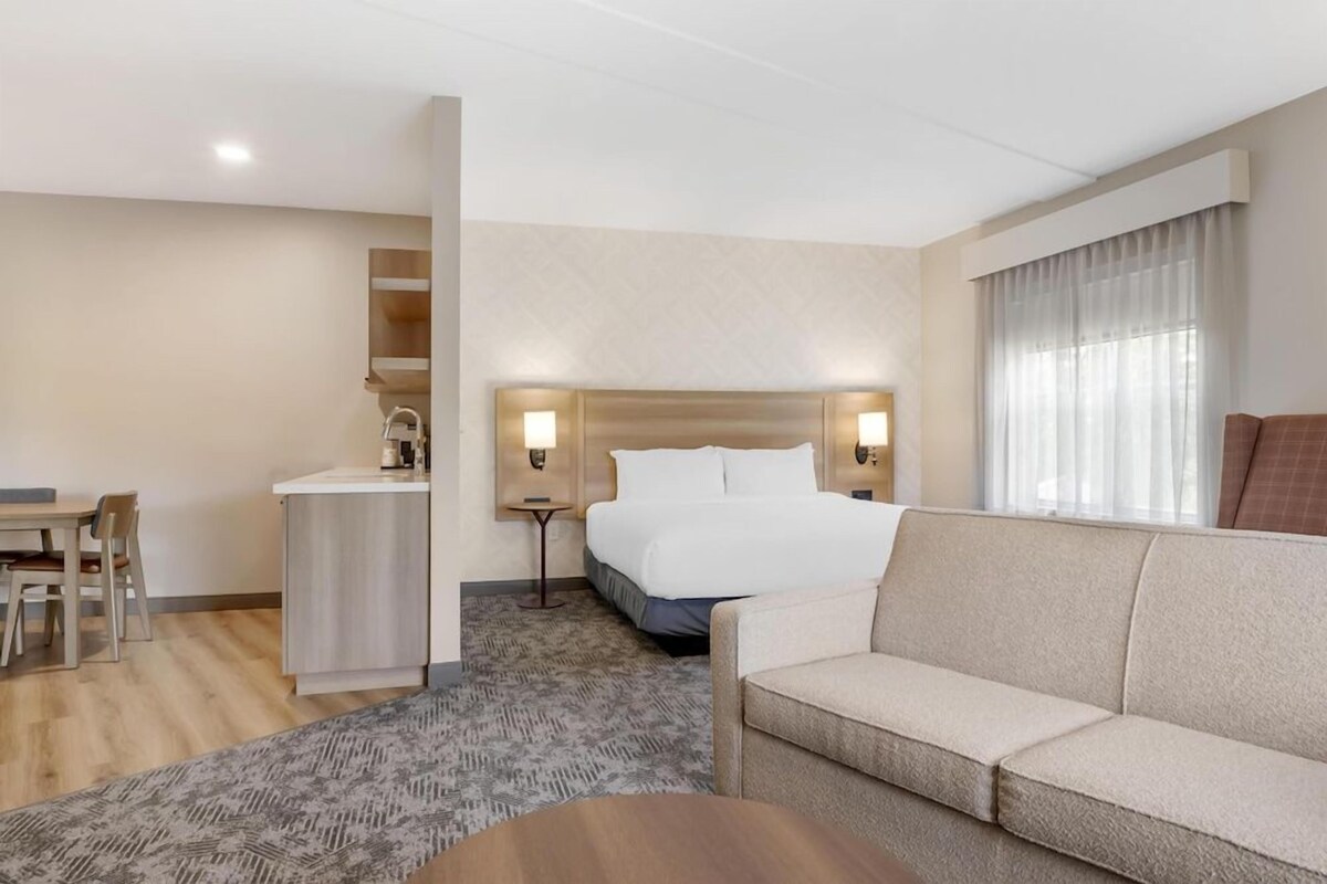 Una habitación de hotel con cama, sofá, escritorio y una mesita.