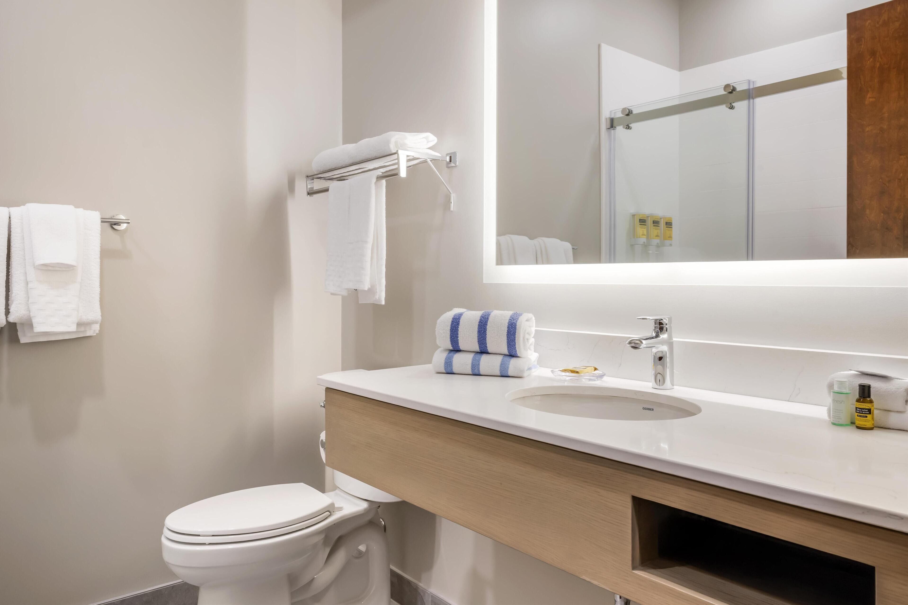 Un baño moderno con inodoro, lavamanos y espejo.