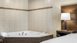 Un baño moderno con una bañera grande, un tocador de madera y una mesita de noche con lámpara.