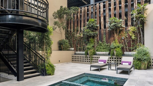 A rooftop pool area with a spiral staircase, lounge chairs, and potted plants. -  DOMA Polanco (Mexico City)