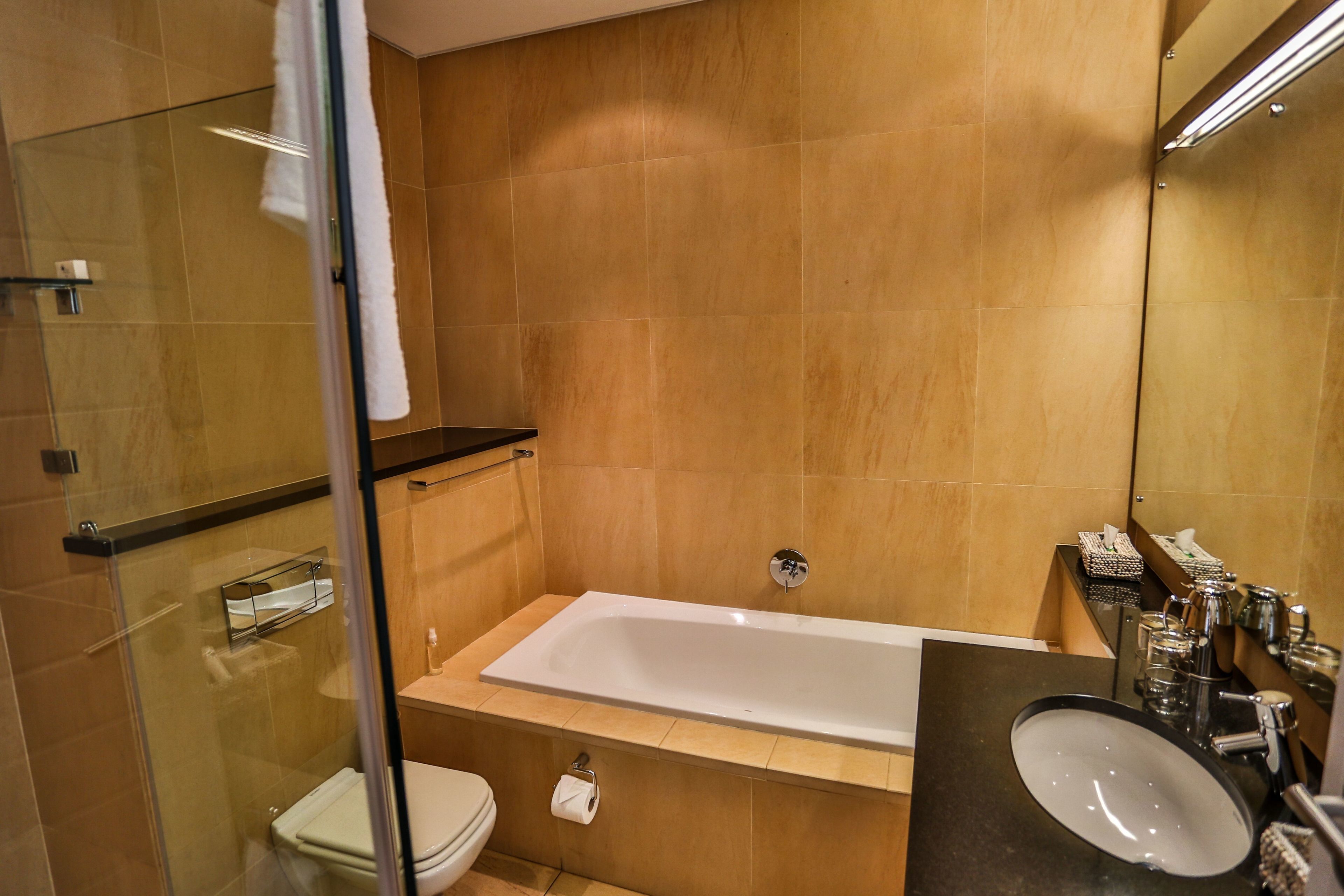 Un baño moderno con ducha envuelta en vidrio, una bañera blanca y un lavamanos negro.