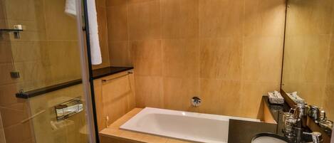 Un baño moderno con ducha envuelta en vidrio, una bañera blanca y un lavamanos negro.