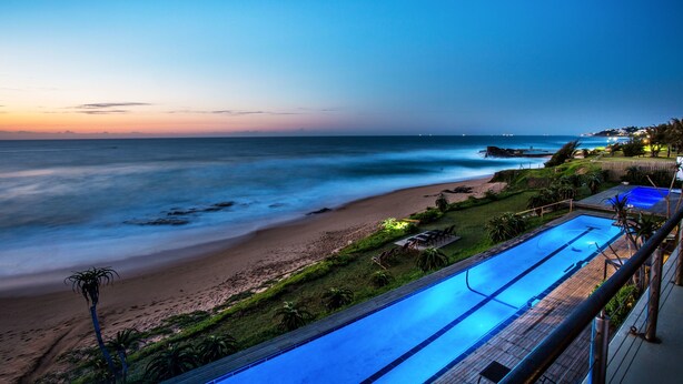 A beach view with a swimming pool and a wooden deck. - Canelands Beach Club (Ballito)