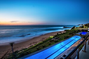 A beach view with a swimming pool and a wooden deck. - Canelands Beach Club (Ballito)