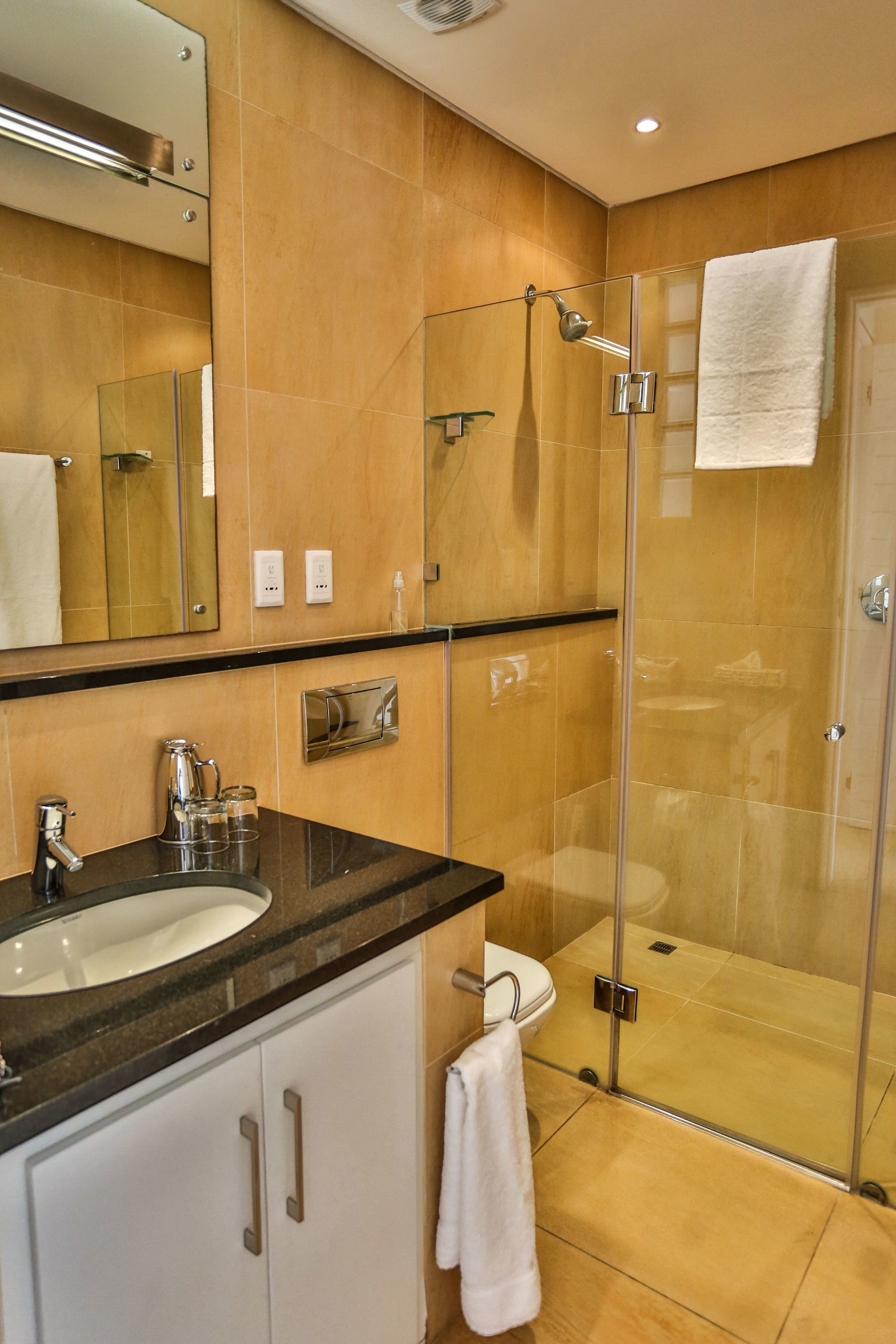 A modern bathroom with a glass-enclosed shower, a sink, and a toilet.