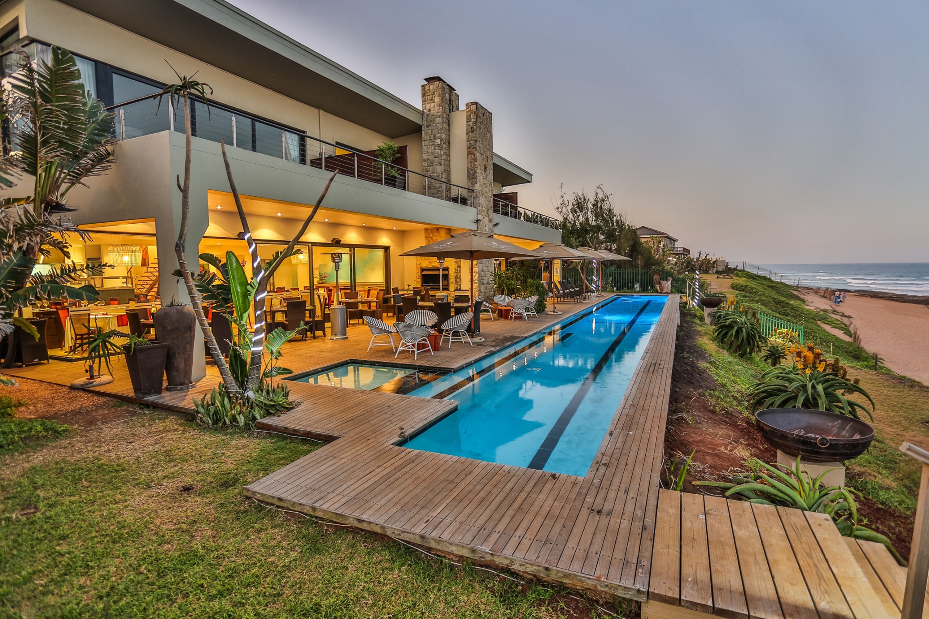Un resort moderno con piscina, mobiliario exterior y vista a la playa.