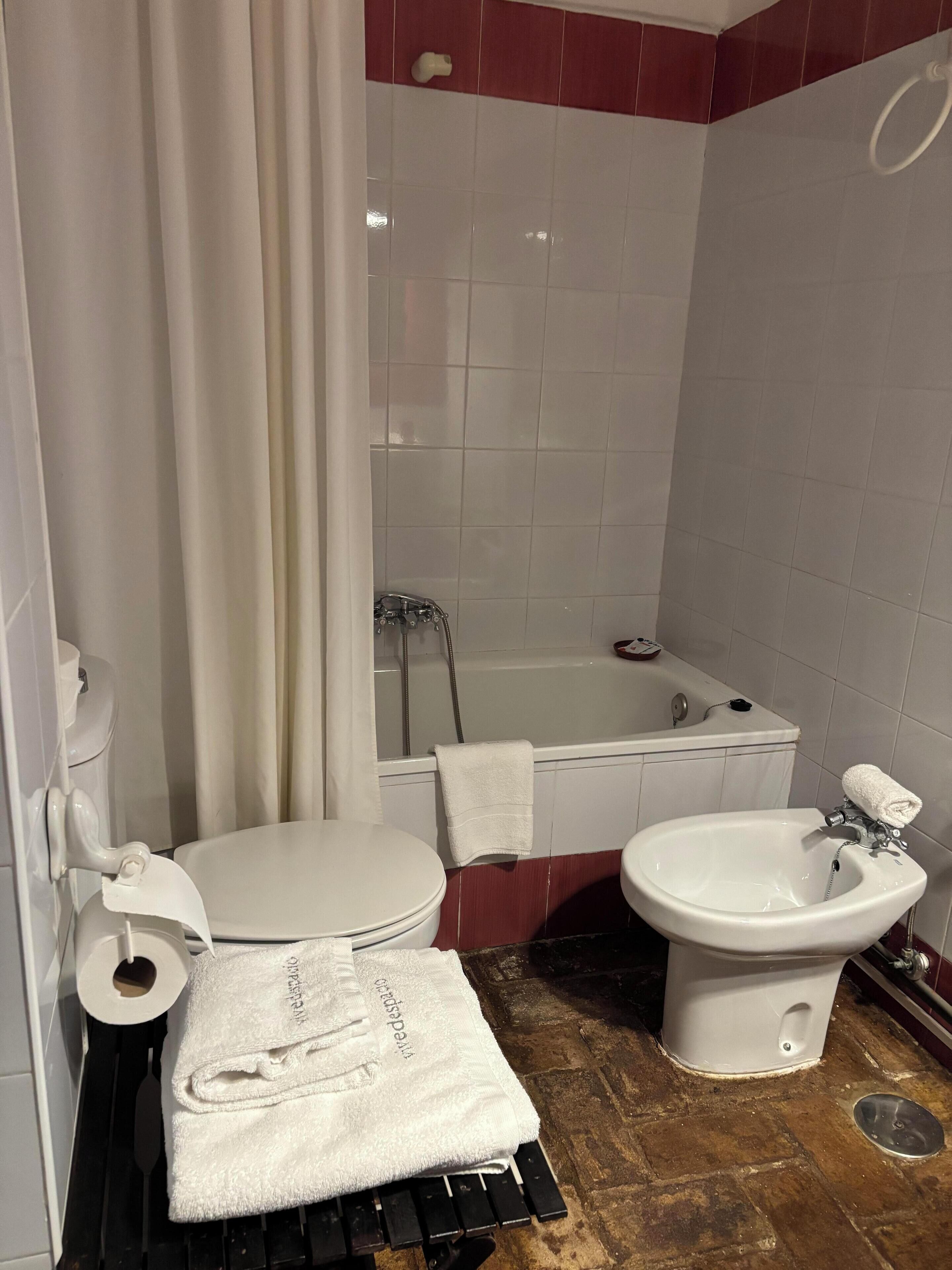 A bathroom with a toilet, bidet, bathtub, and sink.