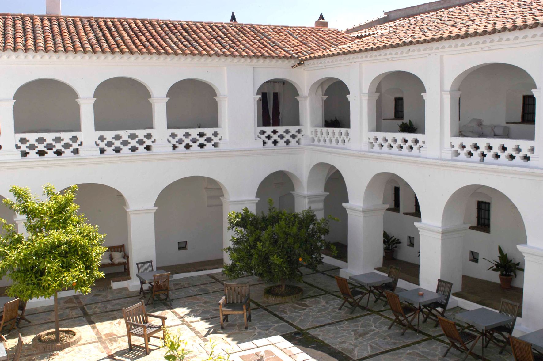 Un patio con arcos blancos, techo de tejas y mobiliario exterior.