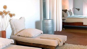 Un dormitorio acogedor con una cama grande, una cama sofá más pequeña y un jarrón decorativo con flores secas.