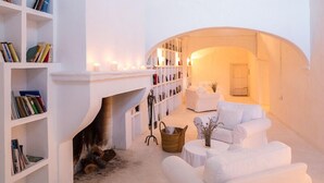Una habitación acogedora y bien iluminada con chimenea, estanterías y asientos cómodos.