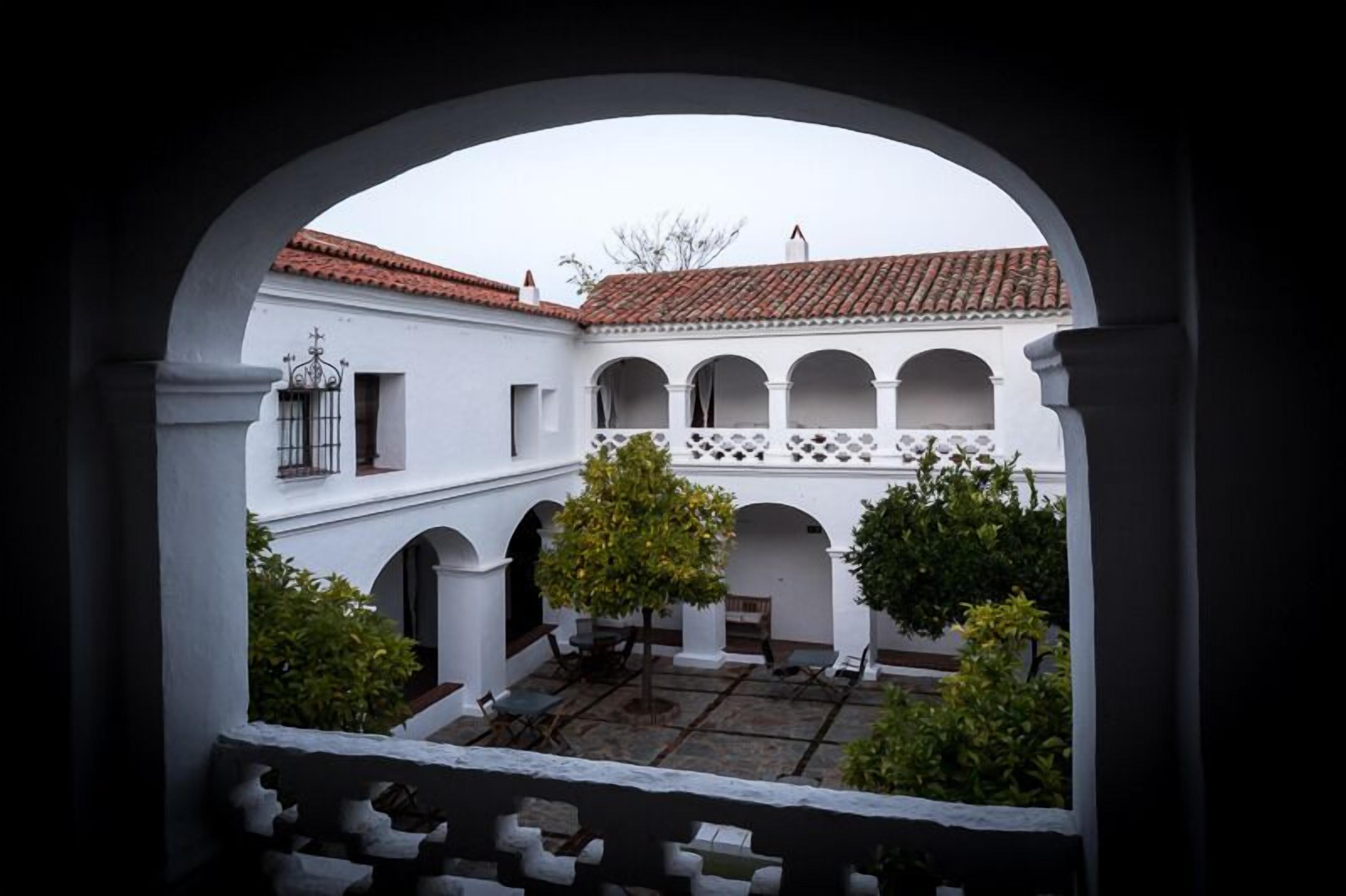Un patio con paredes blancas, techos de tejas rojas y arcos.