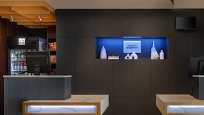 A hotel reception area with a modern design, featuring a reception desk, a minibar, and a television screen displaying the hotel's name. - Courtyard by Marriott New York Manhattan/SoHo (New York)