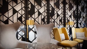A modern lounge area with geometric patterned walls, a round marble table, and two armchairs with lamps. - Courtyard by Marriott New York Manhattan/SoHo (New York)