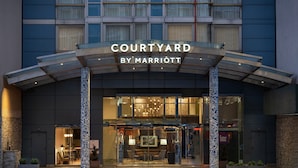 A modern hotel entrance with a glass facade, a covered entrance area, and a sign reading "COURTYARD BY MARRIOTT". - Courtyard by Marriott New York Manhattan/SoHo (New York)